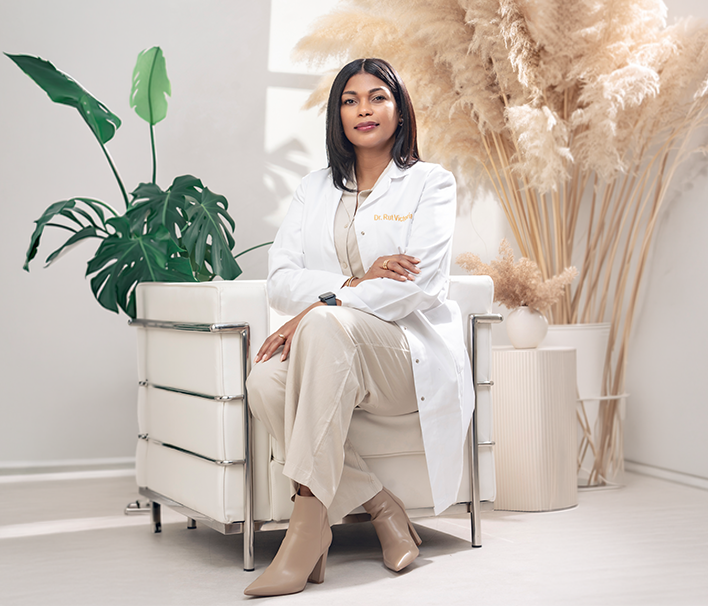 Doctora en medicina estética sentada en una consulta luminosa con bata blanca