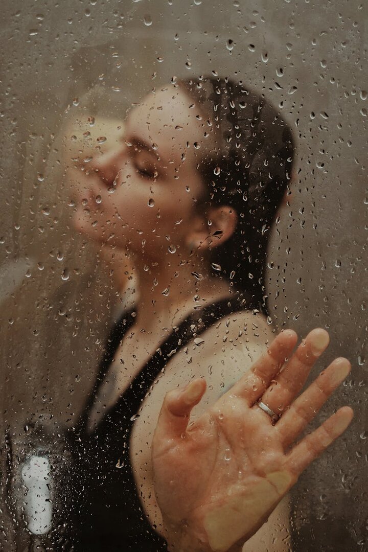 Mujer tras un cristal empañado con gotas de agua, representando sudoración excesiva