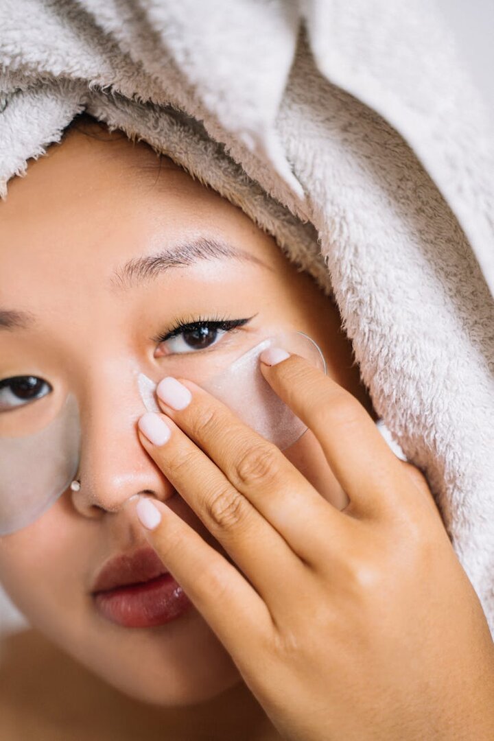 Mujer colocando parches bajo los ojos durante una rutina de cuidado facial