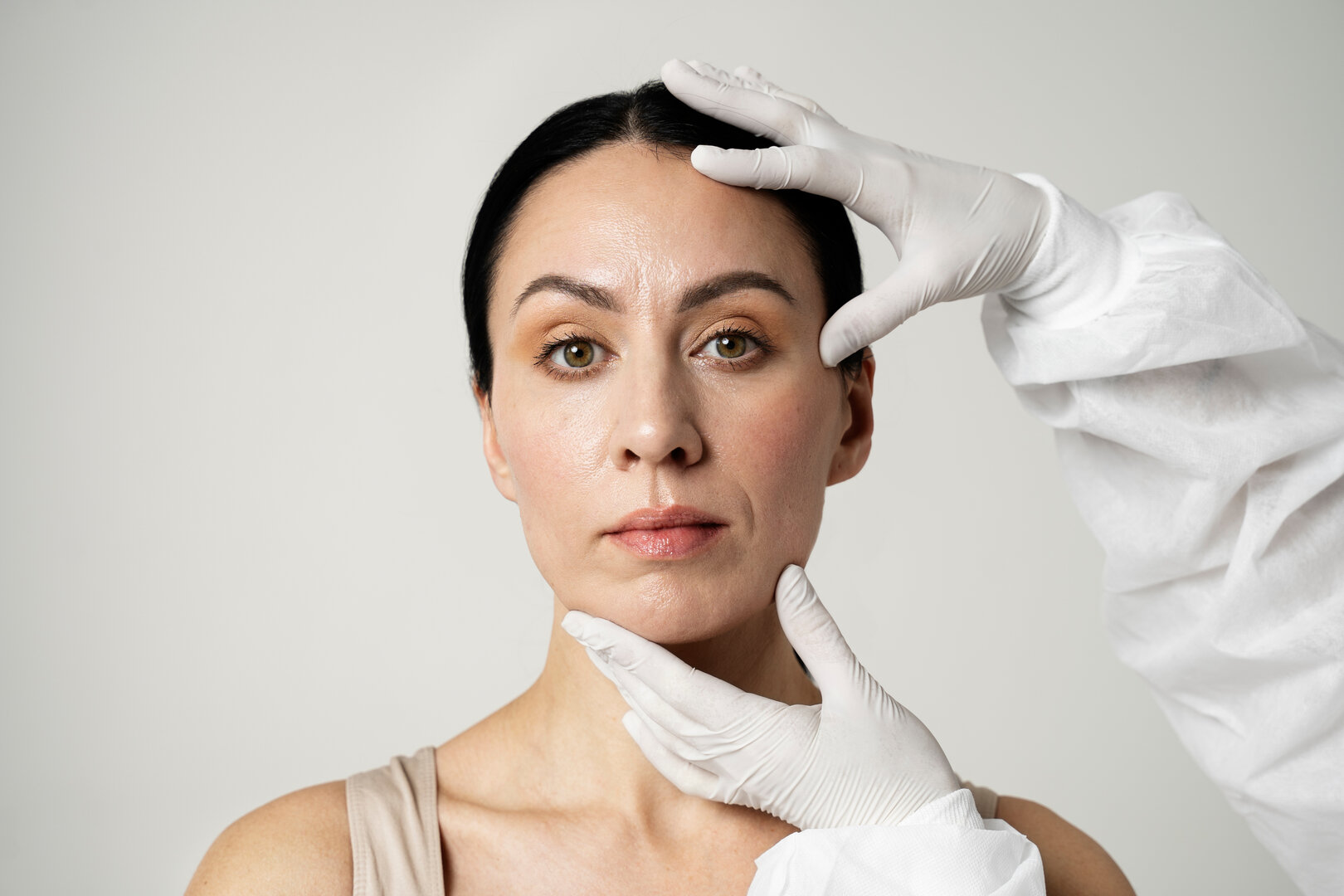 Profesional evaluando el rostro de una mujer durante una valoración estética facial