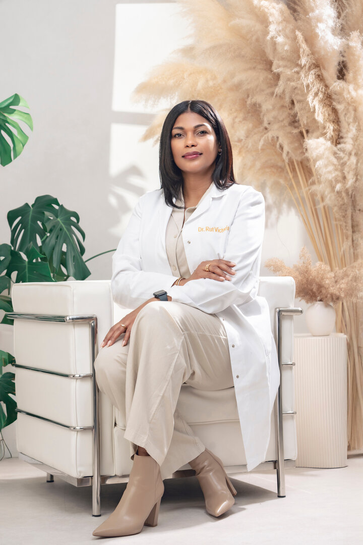 Doctora sentada en consulta de medicina estética con bata blanca y decoración en tonos cálidos